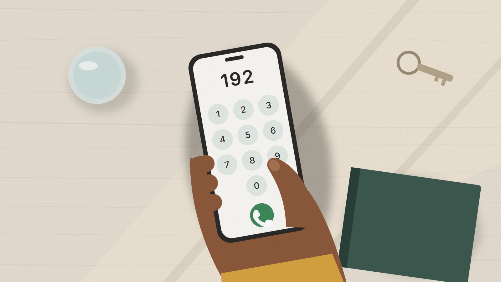 Mão segurando um celular com o número 192 na tela de chamada, sobre uma mesa.
